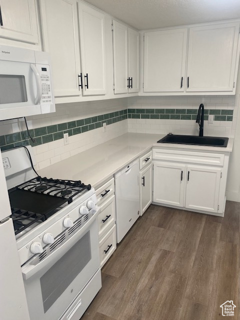 Kitchen with tasteful backsplash, white appliances, sink, dark hardwood / wood-style floors, and white cabinets