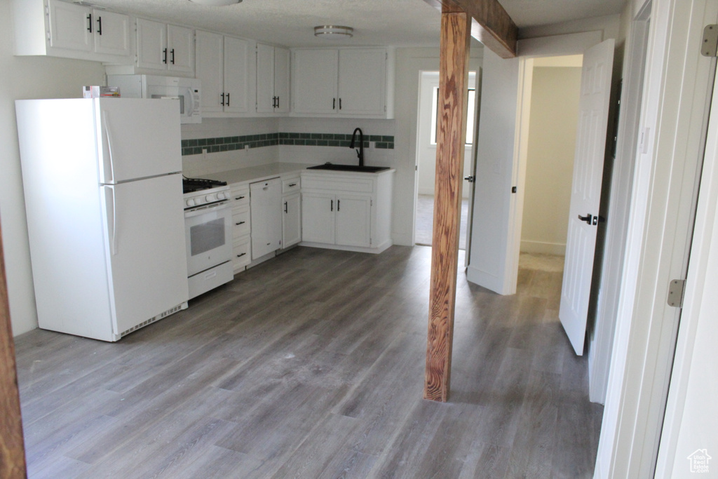 Kitchen with light wood-type flooring, white appliances, and white cabinets