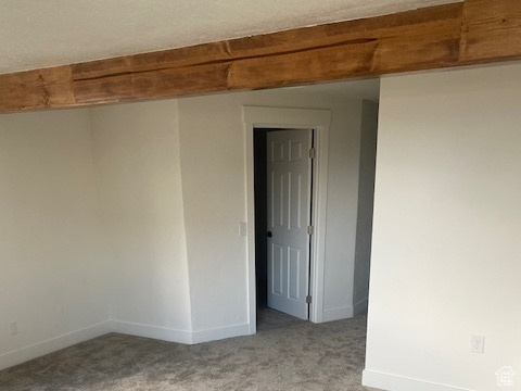 Carpeted spare room with beam ceiling