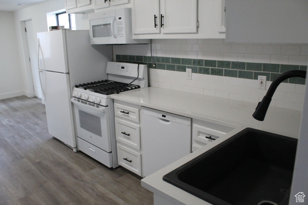 Kitchen featuring dark hardwood / wood-style flooring, white appliances, white cabinets, and tasteful backsplash