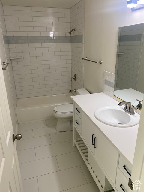 Full bathroom with oversized vanity, tile floors, toilet, and tiled shower / bath combo