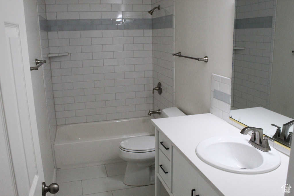 Full bathroom featuring tiled shower / bath combo, toilet, vanity with extensive cabinet space, and tile flooring