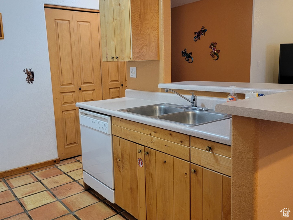 Kitchen featuring sink, dishwasher, and light tile floors