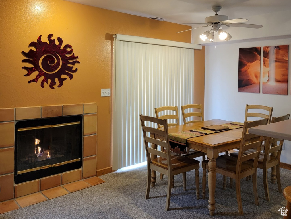 Carpeted dining area with a textured ceiling, ceiling fan, and a fireplace