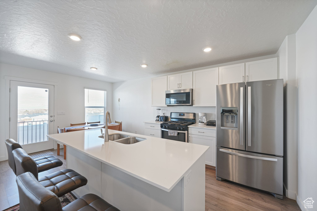Kitchen featuring hardwood / wood-style flooring, stainless steel appliances, sink, and a kitchen island with sink