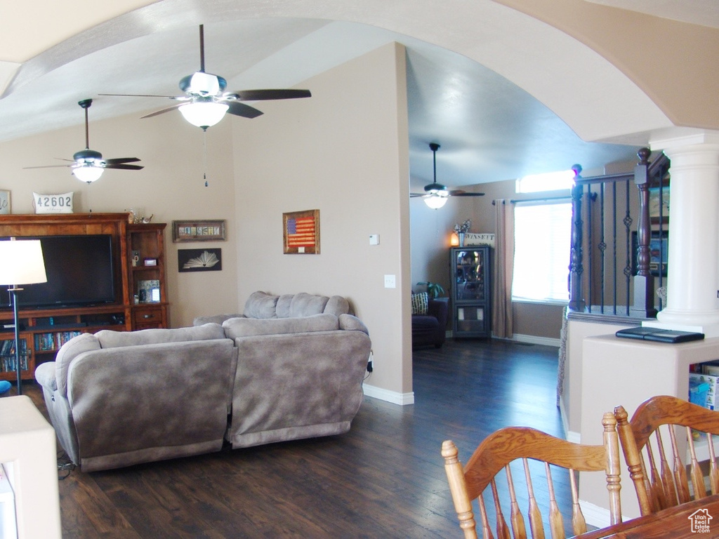 Living room featuring lofted ceiling, dark hardwood / wood-style floors, decorative columns, and ceiling fan