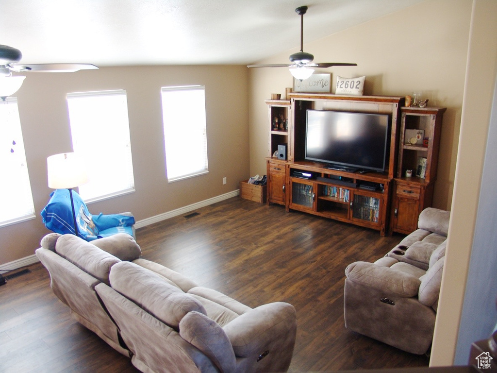 Living room featuring dark hardwood / wood-style flooring, vaulted ceiling, and ceiling fan