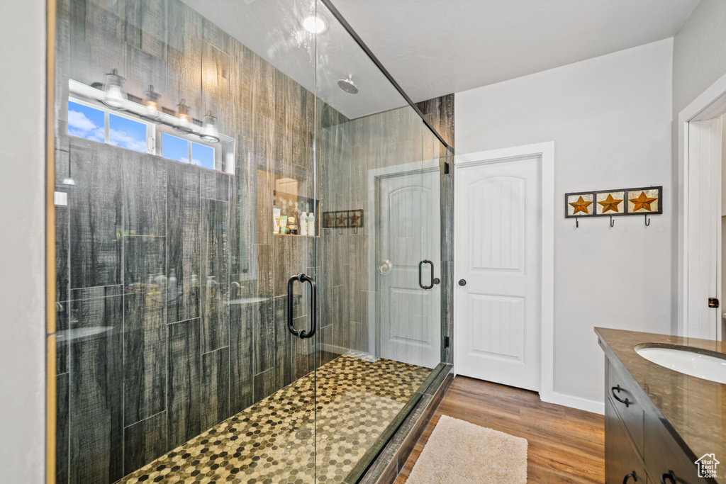 Bathroom featuring hardwood / wood-style flooring, vanity, and walk in shower
