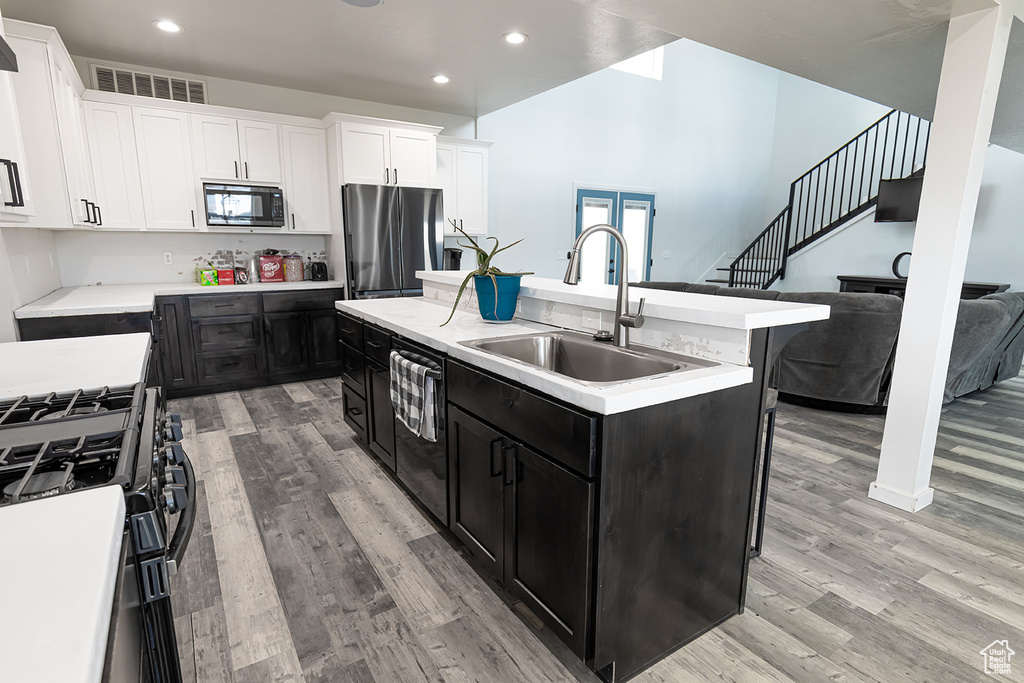 Kitchen featuring appliances with stainless steel finishes, light wood-type flooring, an island with sink, and sink