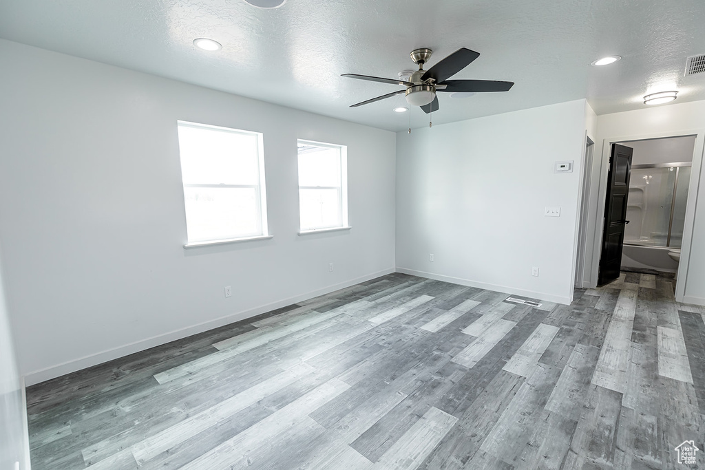 Empty room with a textured ceiling, light hardwood / wood-style floors, and ceiling fan