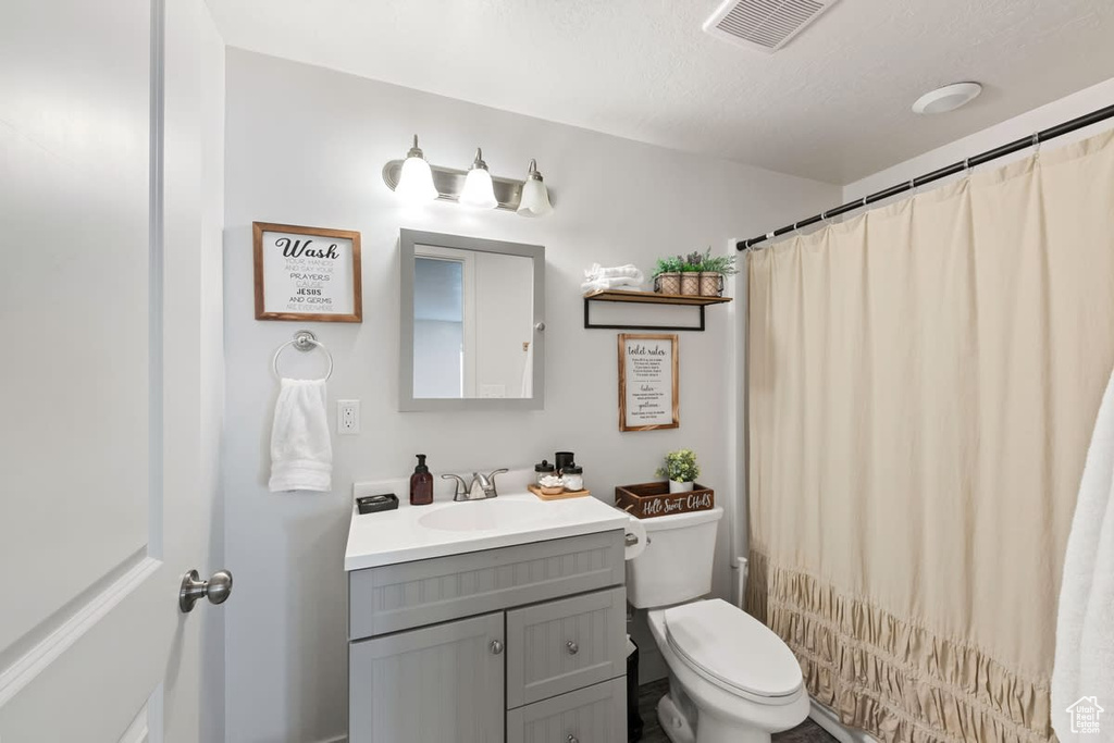 Bathroom with oversized vanity, a textured ceiling, and toilet