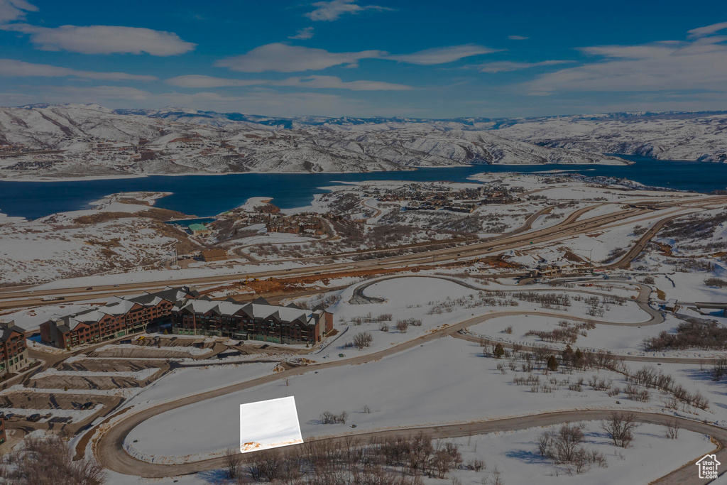 Snowy aerial view featuring a water and mountain view