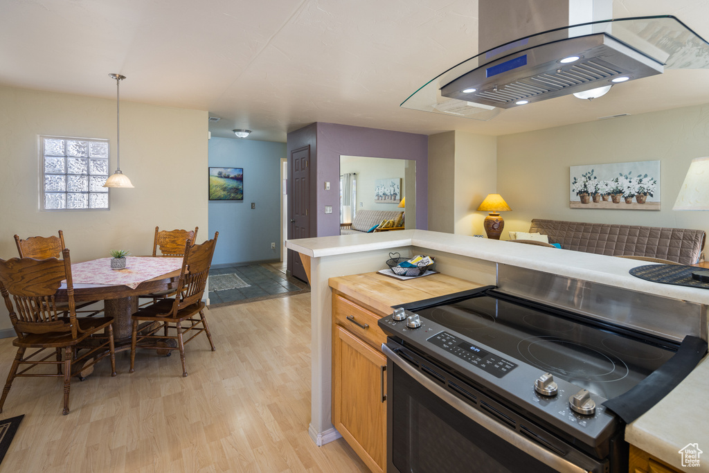 Kitchen featuring electric range oven, hanging light fixtures, and light hardwood / wood-style flooring