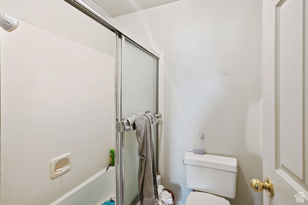 Bathroom with bath / shower combo with glass door and toilet