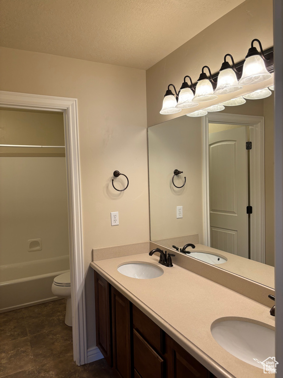 Full bathroom featuring a textured ceiling, dual bowl vanity, toilet, tile flooring, and shower / bathing tub combination