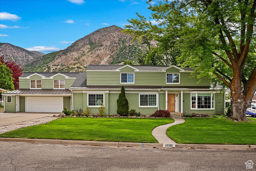 Front facade featuring a front yard, a garage, and a mountain view