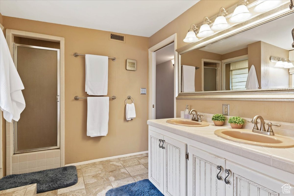 Bathroom featuring dual vanity, walk in shower, and tile floors