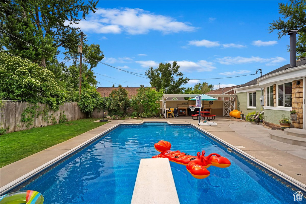 View of swimming pool with a diving board, a yard, and a patio area