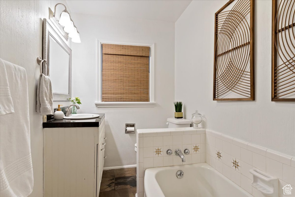 Bathroom featuring vanity, toilet, a washtub, and tile floors
