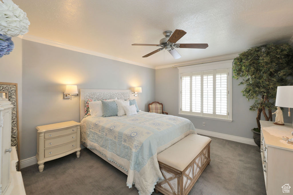 Carpeted bedroom featuring a textured ceiling, crown molding, and ceiling fan