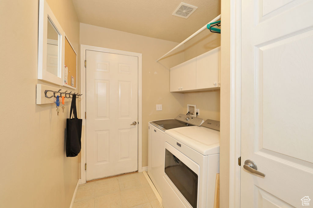 Laundry area with washer hookup, cabinets, washing machine and clothes dryer, and light tile floors