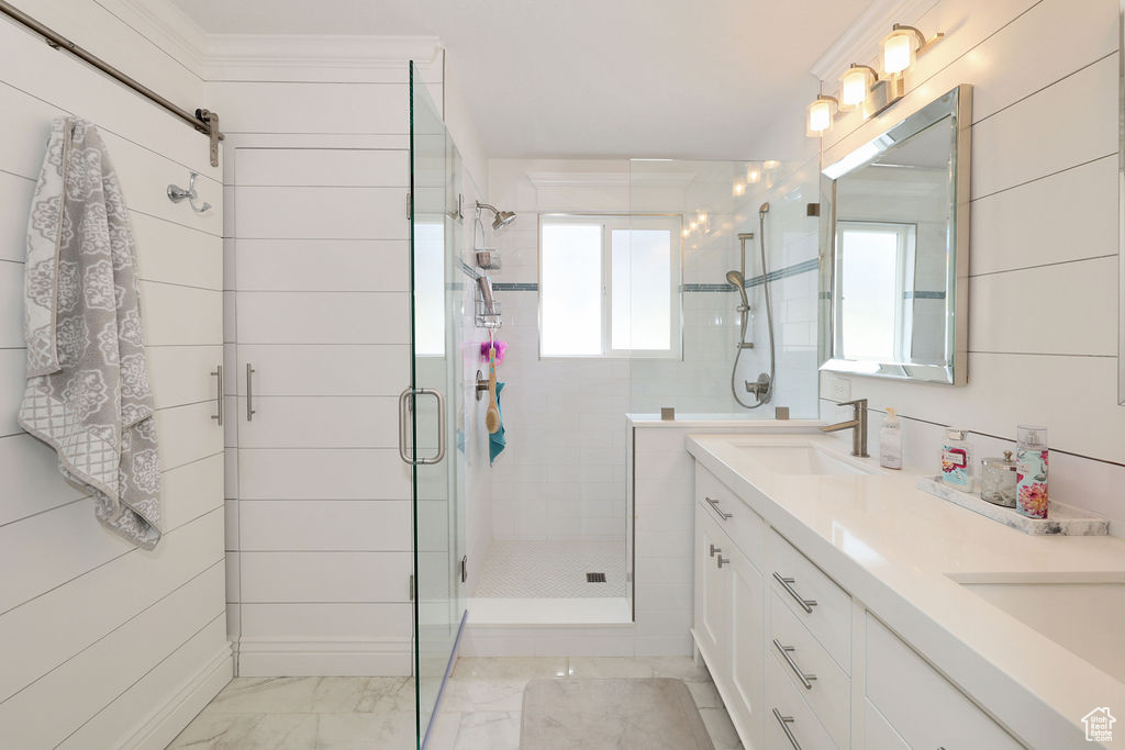 Bathroom featuring oversized vanity, tile flooring, double sink, and a shower with door