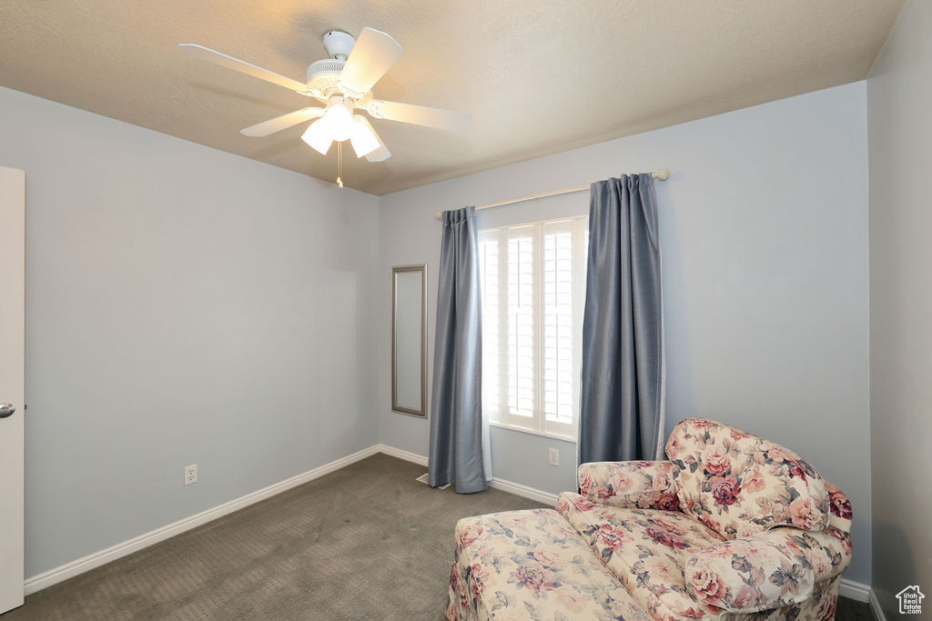 Sitting room with dark carpet and ceiling fan