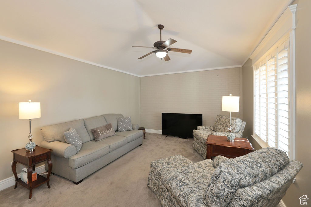Carpeted living room featuring ornamental molding, lofted ceiling, and ceiling fan