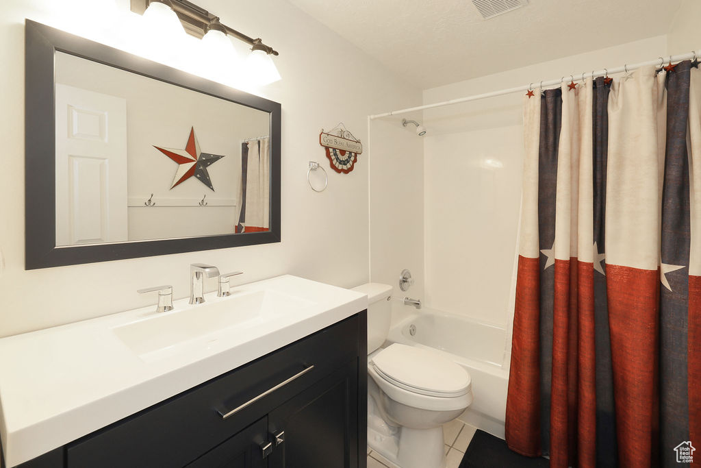 Full bathroom featuring tile floors, vanity, toilet, and shower / tub combo
