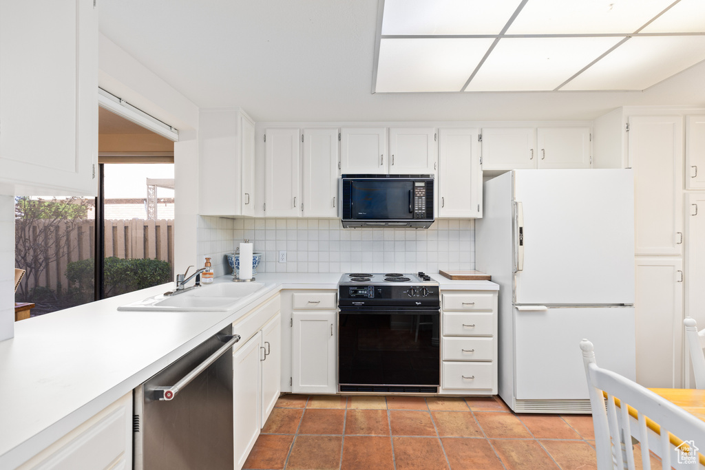 Kitchen featuring white cabinets, dishwasher, sink, white refrigerator, and range with electric stovetop