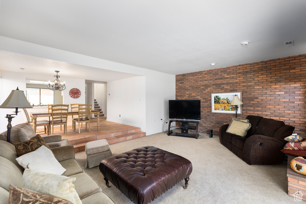 Carpeted living room with brick wall and a notable chandelier