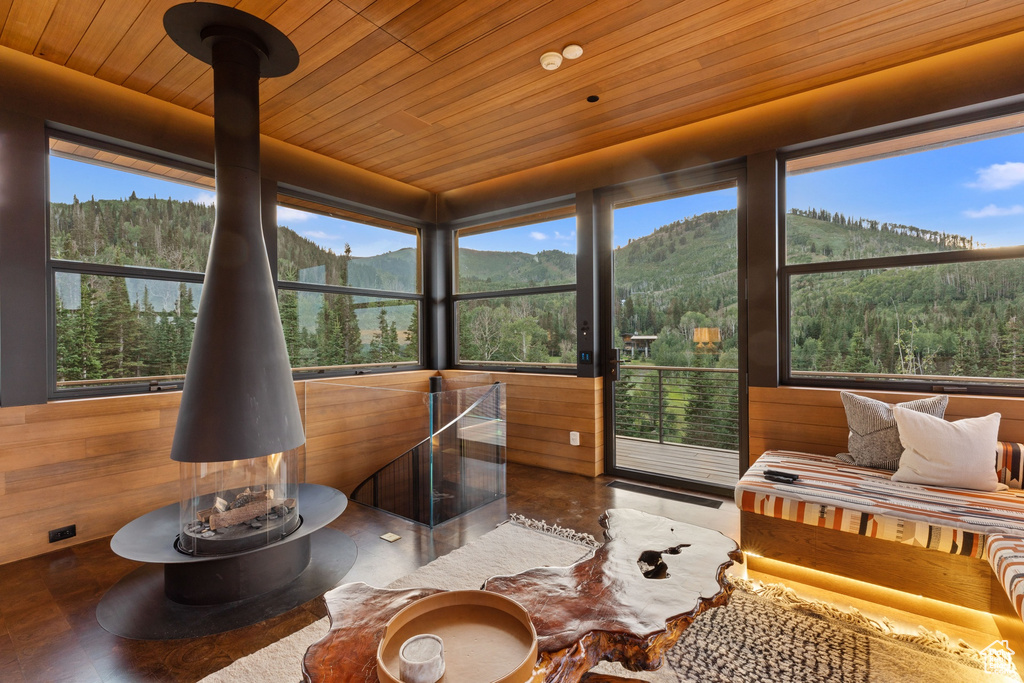 Sunroom / solarium with a wood stove, a healthy amount of sunlight, wood ceiling, and a mountain view