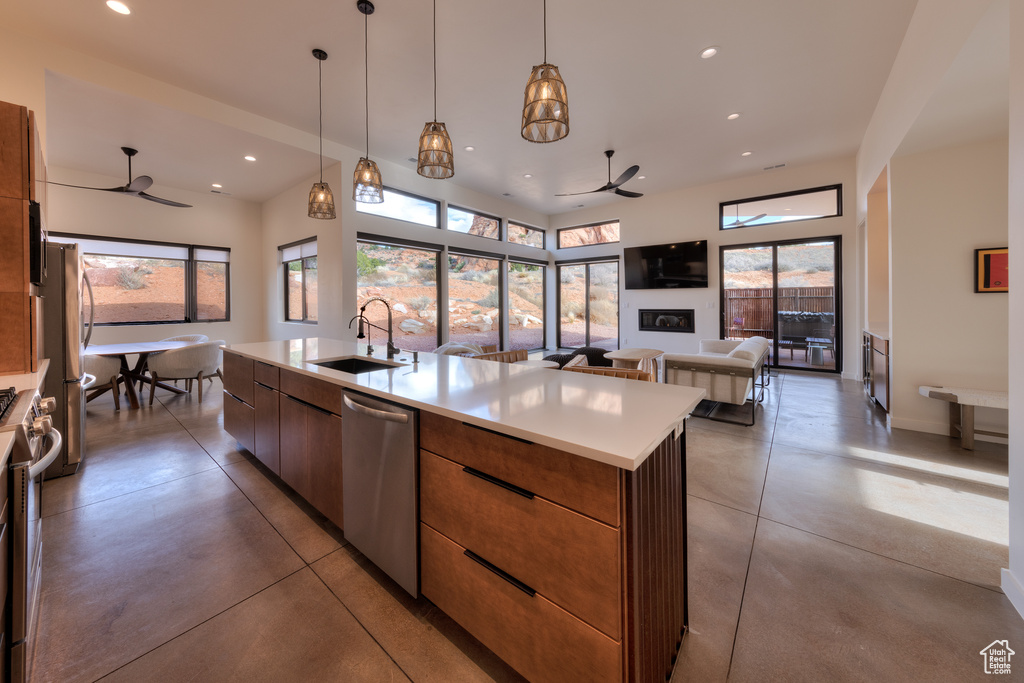 Kitchen featuring a kitchen island with sink, sink, decorative light fixtures, appliances with stainless steel finishes, and ceiling fan