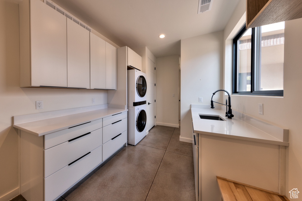 Laundry room featuring stacked washer / drying machine, tile flooring, and sink