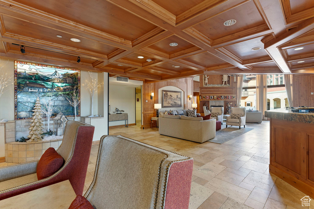 Living room with beam ceiling, coffered ceiling, wooden walls, and light tile floors