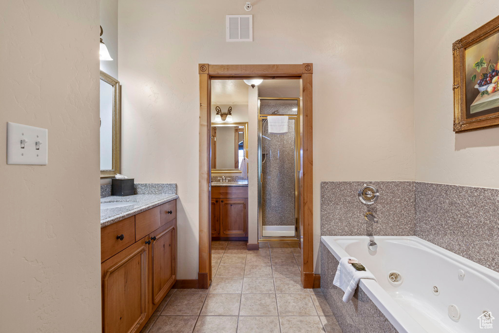 Bathroom with tile flooring, a shower with shower door, and vanity