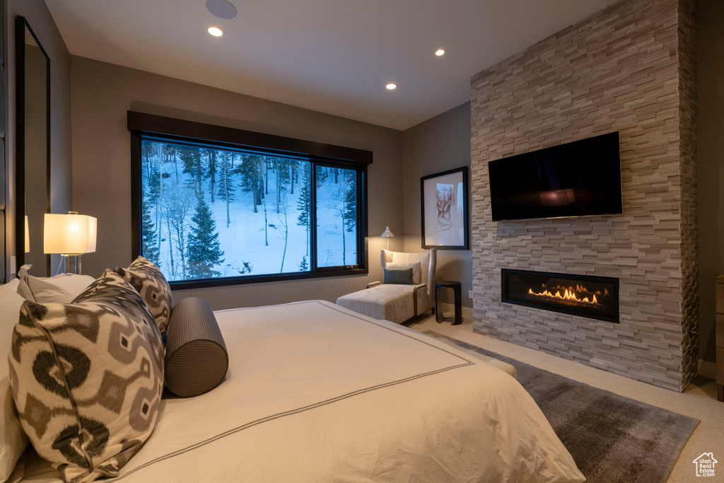 Bedroom with light colored carpet and a stone fireplace