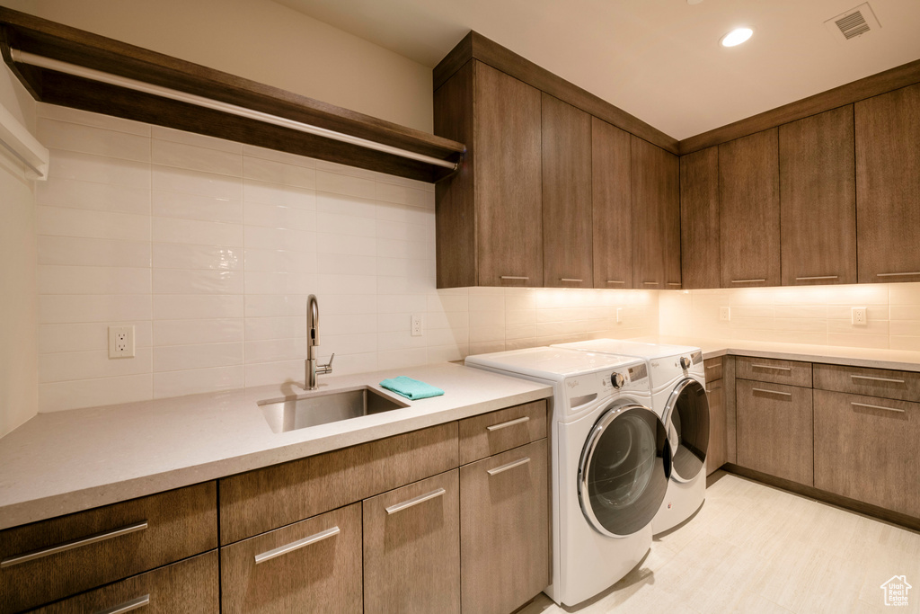 Washroom featuring cabinets, washer and clothes dryer, and sink