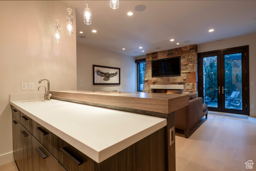 Interior space with sink, decorative light fixtures, light hardwood / wood-style floors, kitchen peninsula, and a fireplace