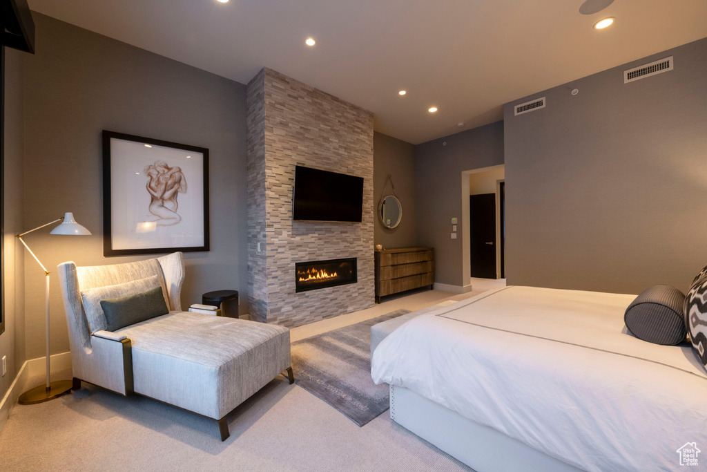 Bedroom featuring light carpet and a stone fireplace