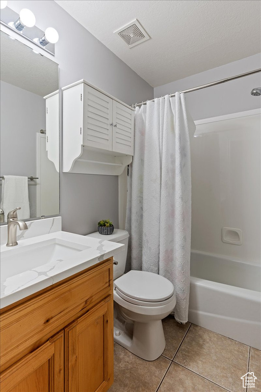 Full bathroom featuring shower / bathtub combination with curtain, tile floors, a textured ceiling, toilet, and oversized vanity