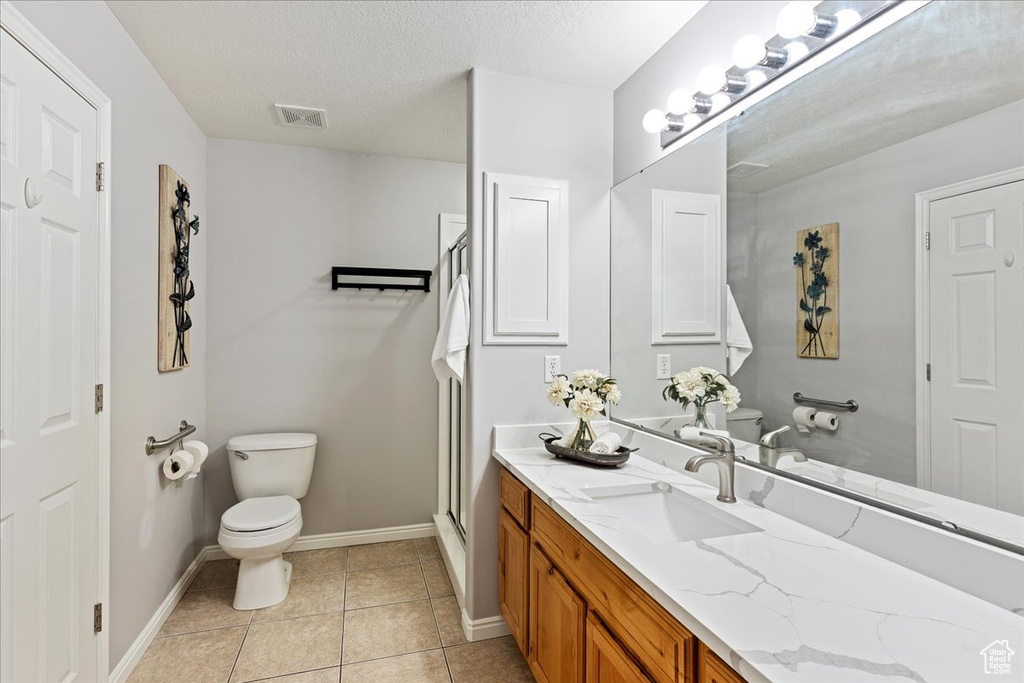 Bathroom featuring a textured ceiling, toilet, tile flooring, and large vanity