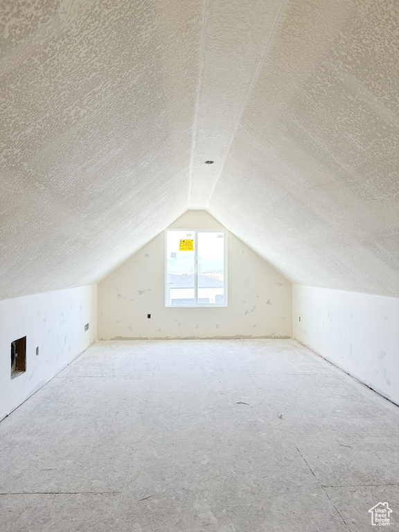 Additional living space with a textured ceiling and lofted ceiling