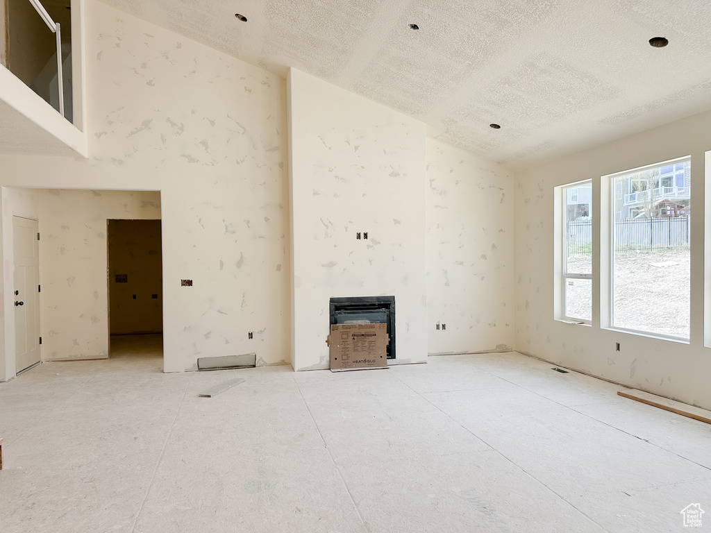 Unfurnished living room featuring high vaulted ceiling