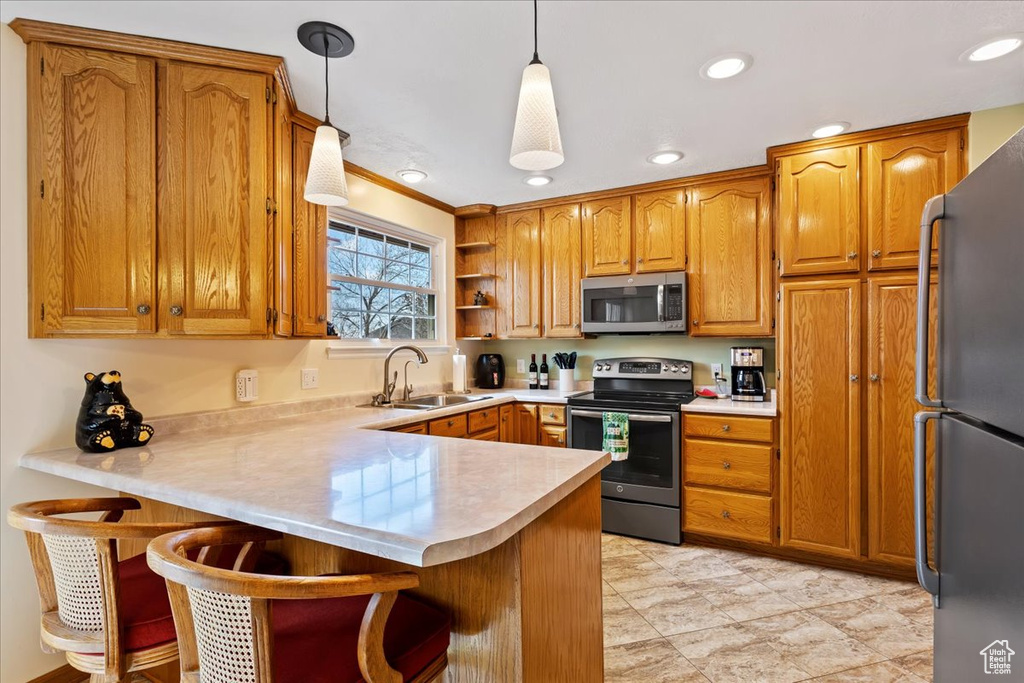 Kitchen featuring light tile flooring, sink, decorative light fixtures, a kitchen bar, and appliances with stainless steel finishes