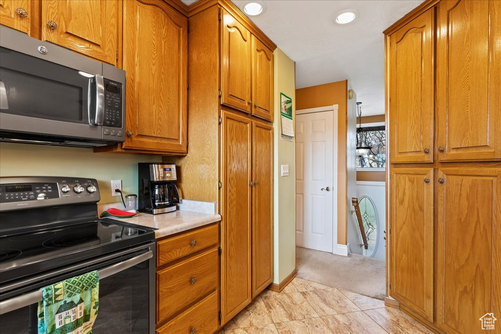 Kitchen featuring washer / clothes dryer, stainless steel appliances, and light tile floors