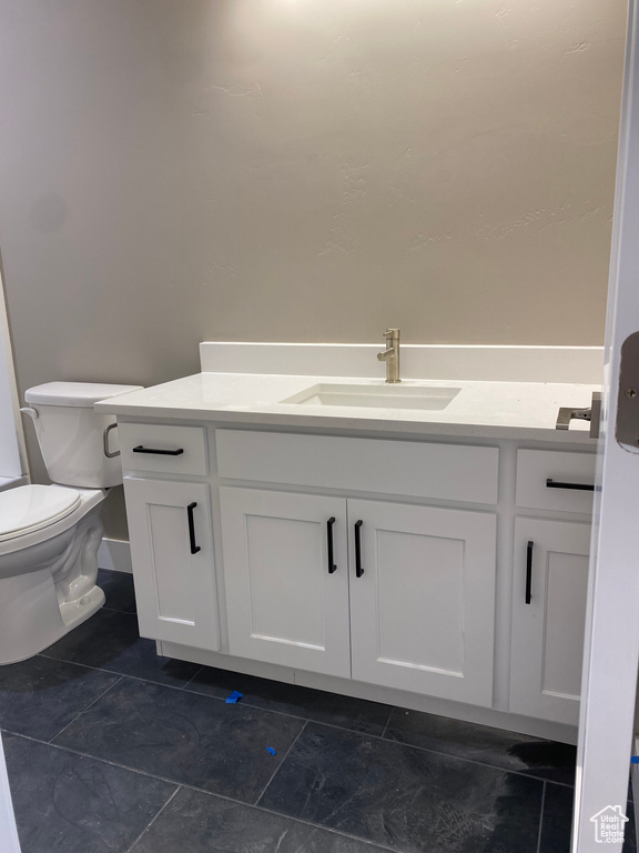 Bathroom featuring vanity, tile flooring, and toilet