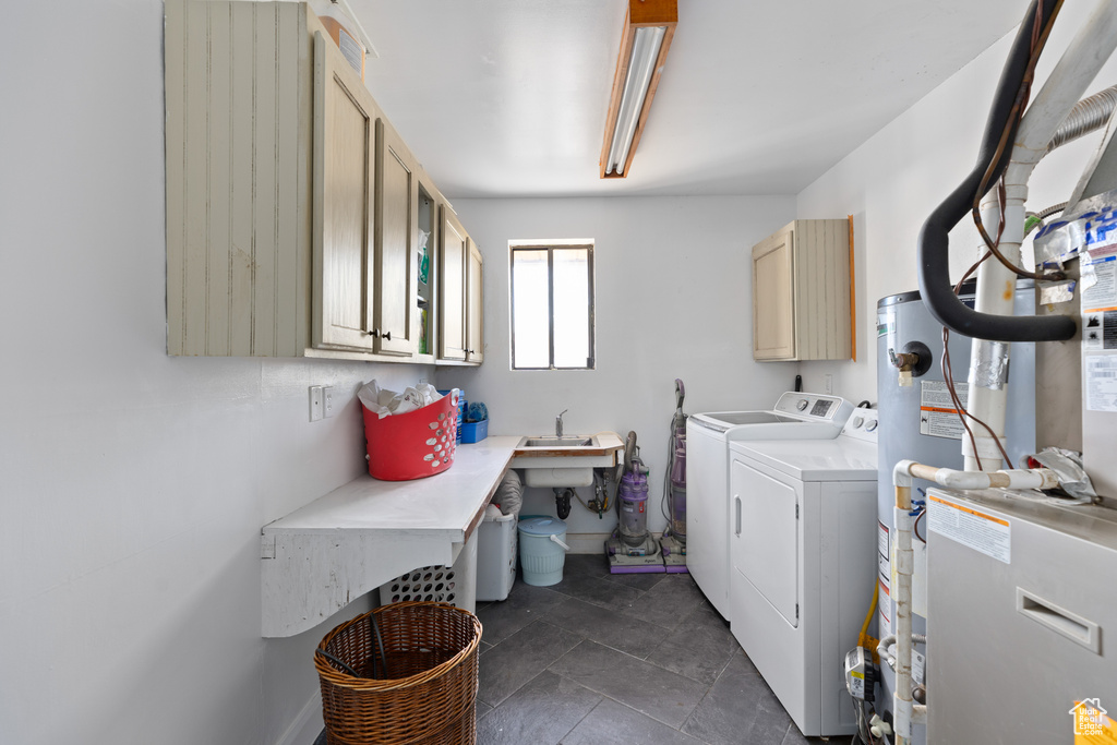 Washroom featuring washing machine and clothes dryer, cabinets, sink, and dark tile flooring