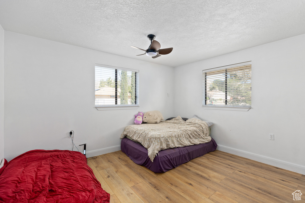 Bedroom with multiple windows, light wood-type flooring, and ceiling fan