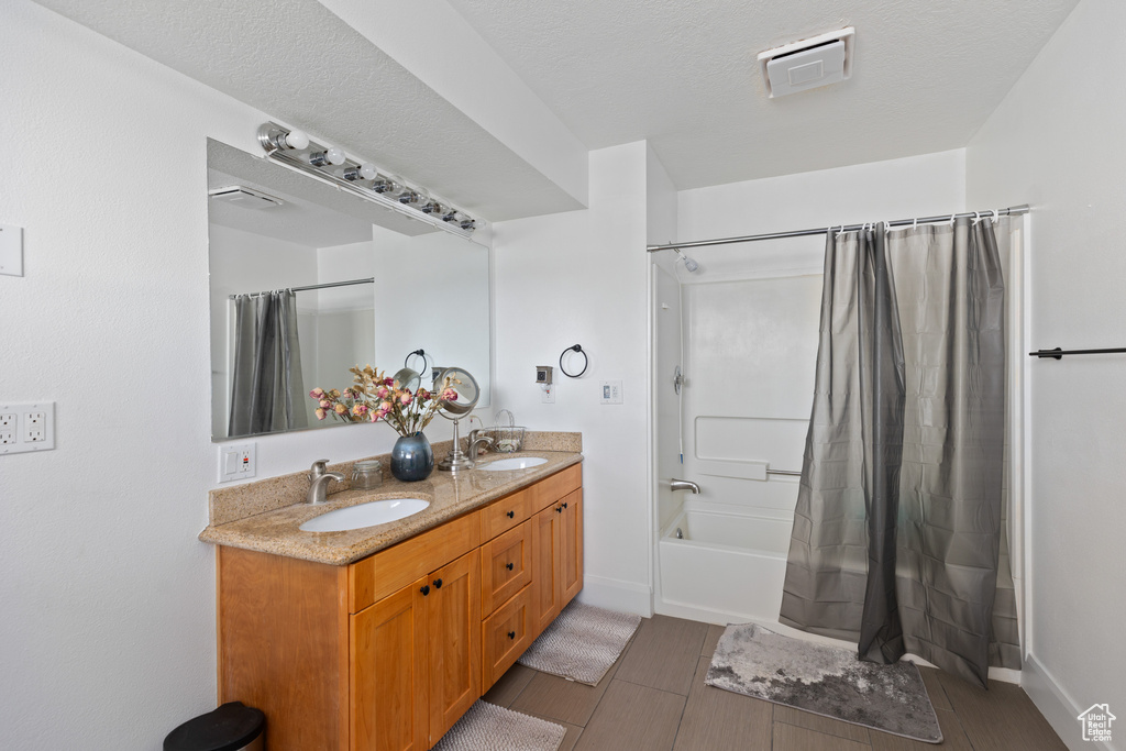 Bathroom with vanity with extensive cabinet space, shower / bath combination with curtain, tile floors, and double sink